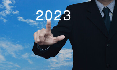 Businessman pressing 2023 letter over blue sky with white clouds, Business happy new year 2023 cover concept