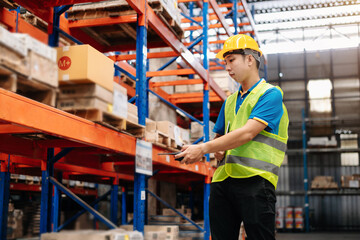  Storage worker in uniform Wearing Hard Hat Checks Stock and Inventory with Digital Tablet Computer in the Retail Warehouse full of Shelves with Goods.