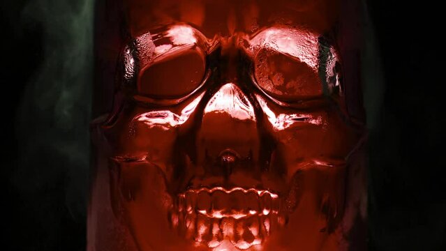 Alchemical Experiments in a Glass Skull. Bright, rich blood-red glass vessel in the form of the skull, from which are evaporation and slow down the edges on a black background