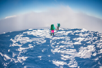 two climbers climb the mountain. Two girls climb a snow-covered mountain.