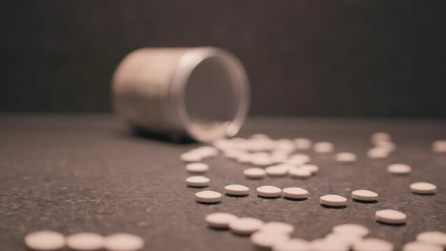 Pills from container spilling onto table, medicine