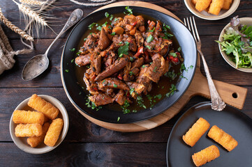 Brown stew chicken with croquettes and salad on wooden table. Top view