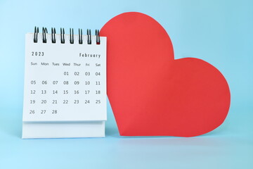 Selective focus of February 2023 desk calendar with big red heart shape on blue background with...