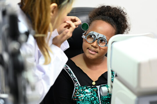 Ophthalmologist testing vision or sight of cute little girl in modern ophthalmology clinic