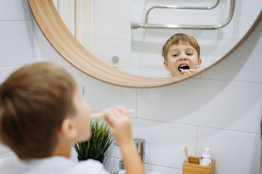 cute 5 years old boy brushing teeth with bamboo tooth brush in bathroom. Image with selective focus