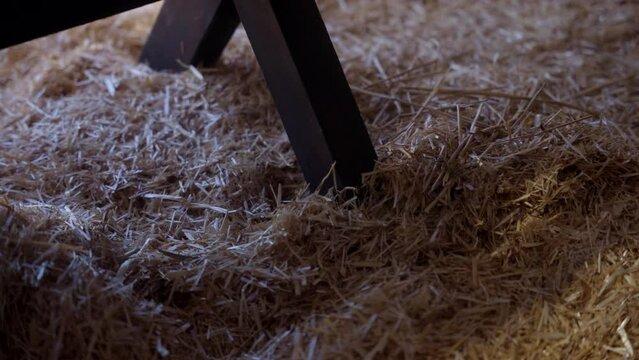 The leg of a manger sitting in hay at night.