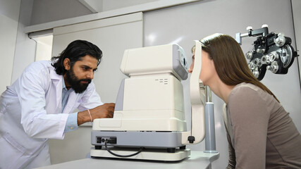 Image of caucasian woman checking eyesight on auto refractor in ophthalmologist clinic. Eye health check and ophthalmology concept