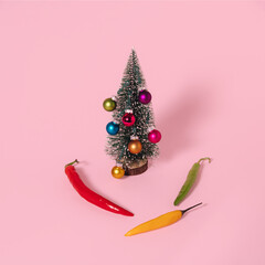 Decorated Christmas tree and hot peppers on pastel pink background