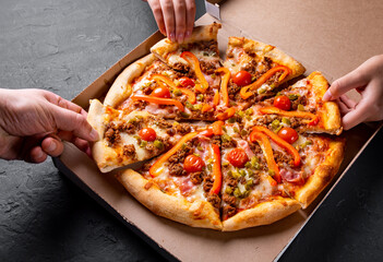 Hands takes a slice of Pizza with Mozzarella cheese, Bolognese sauce, minced meat, pepper, tomato, bacon and vegetables in paper box