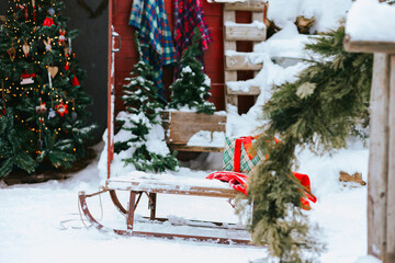 backyard porch of the rural house decorated for Christmas, winter still life, sleighs and gifts in...