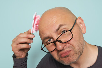 Bald, bearded man with glasses came to the doctor with a problem of baldness, holding a baby comb...