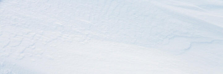 Beautiful winter background with snowy ground. Natural snow texture. Wind sculpted patterns on snow surface. Wide panoramic texture for background and design.