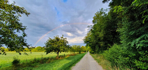 Rainbow over Thunderclouds over a field path in the morning in Siebenbrunn near Augsburg before a rain in the morning