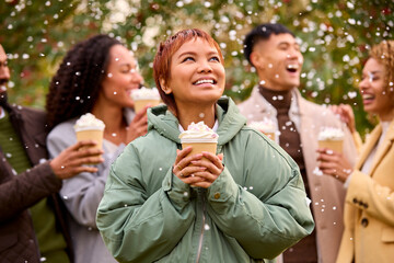 Group Of Friends Wearing Coats Standing Outside In Snow Holding Takeaway Hot Chocolate Drinks