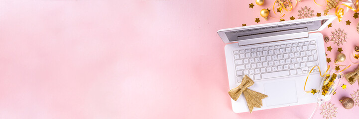 Christmas and New Year work space flat lay with laptop and gold holiday decoration on pink trendy background. Office holiday corporate holiday invitation, preparation for christmas New Year party