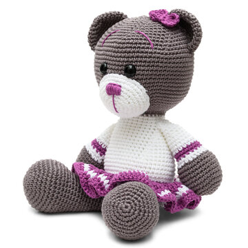 Urso de pel&uacute;cia com la&ccedil;o nas cores cinza, branco e lil&aacute;s, confeccionado na t&eacute;cnica de croch&ecirc; amigurumi, sentado de perfil 