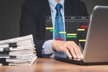 A Project manager working on a laptop and updating tasks and milestones progress planning with a Gantt chart scheduling