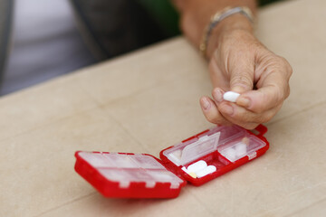Senior woman hands take pills from box. Healthcare and old age concept with medicines. Medicaments on table
