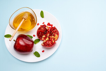 Jewish New Year Rosh Hashanah Traditional blue background with red apple, pomegranate and honey on a plate