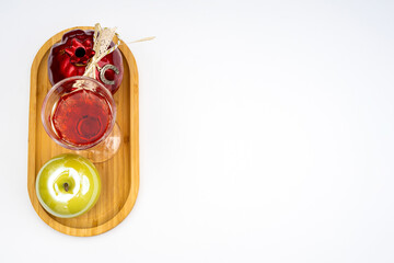 White background with an apple, a pomegranate and a glass of red wine on a wooden tray as a Rosh Hashanah concept. Pomegranate, Nar Bayramı New Harvest Festival