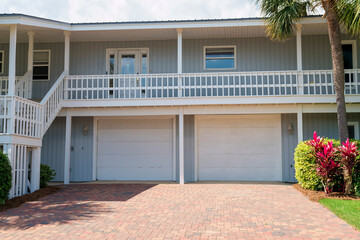 Destin, Florida- Two attached garage below a veranda with ornate glass on the front door