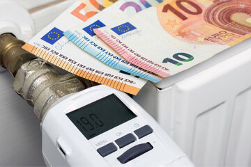 Euro money banknotes on heating radiator with digital thermostat.