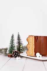 Traditional German layered winter cake called 'Baumkuchen' glazed with chocolate, surrounded by...