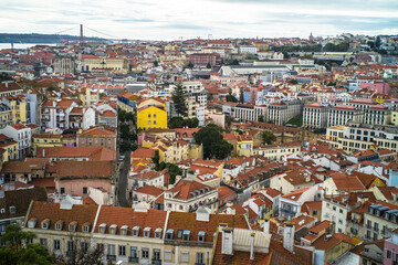 Fototapeta na wymiar historic buildings of the old town of lisbon. Old colorful buildings, narrow streets, historic churches. Tiled roofs. View from the top of the tenement houses and monuments. Cloudy day 