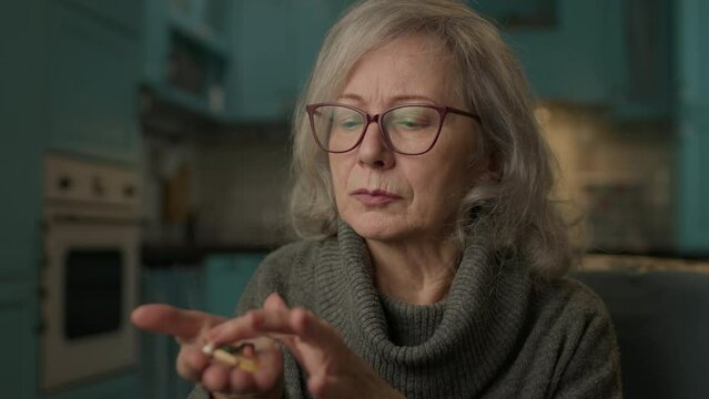 Senior Woman Counting Pills On Hand. 60s woman taking care of health.
