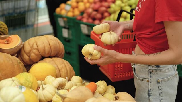 close-up woman chooses a small pumpkin in a supermarket