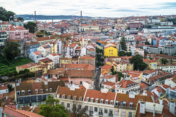 Fototapeta na wymiar historic buildings of the old town of lisbon. Old colorful buildings, narrow streets, historic churches. Tiled roofs. View from the top of the tenement houses and monuments. Cloudy day 