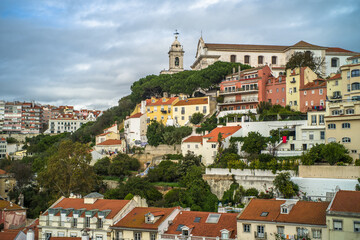 Obraz premium historic buildings of the old town of lisbon. Old colorful buildings, narrow streets, historic churches. Tiled roofs. View from the top of the tenement houses and monuments. Cloudy day 