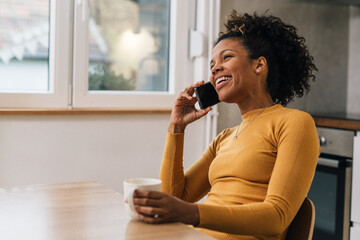 Adult black woman talks on the phone at home