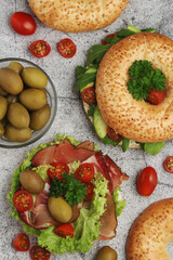 Sesame bagels with tomatoes, ham and olives
