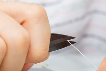 Female hands of a master tailor cuts a thread with scissors