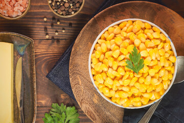 Sweet corn kernels in small bowl. Served with butter, Himalayan salt,  peppercorns and parsley. Top view with close up.