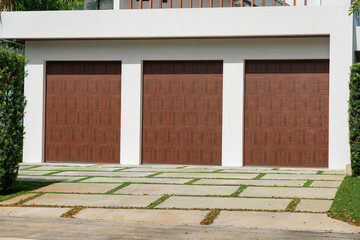 Three dark wood garage doors with grass pavement driveway in Miami, Florida
