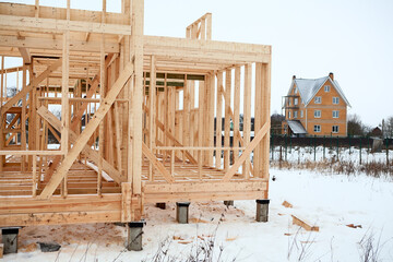 Conventional house construction, bare frame with concrete pile foundation at winter season