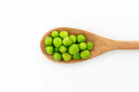 green peas isolated. fresh organic vegetables. on a wooden spoon. top view