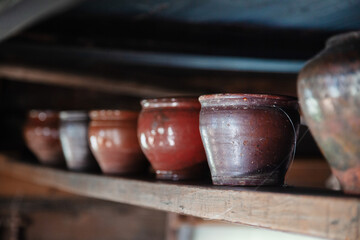 Colorful old clay pots are on the shelf. Blurred background