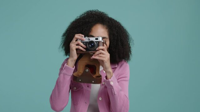 Portrait of a woman taking photos with a camera. Cheerful, smiling girl during the session in colorful studio. High quality 4k footage