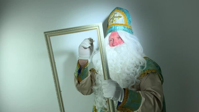 saint nicholas draws in an empty frame with a beautiful white pen a fabulous letter magical action he has a white fluffy beard a suit blue with gold he comes before santa claus Christmas
