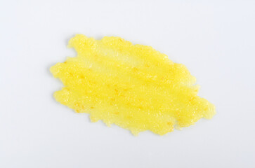 Yellow lemon face or body exfoliating scrub texture. Beauty mask smear on white background. Cosmetic product swatch close-up.