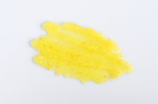 Yellow Lemon Face Or Body Exfoliating Scrub Texture. Beauty Mask Smear On White Background. Cosmetic Product Swatch Close-up.