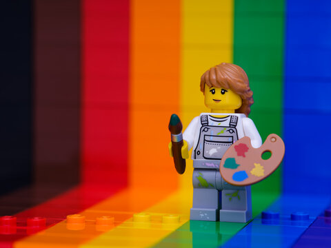 Tambov, Russian Federation - November 07, 2022 A Lego painter minifigure with a paintbrush and a palette standing against a rainbow backdrop