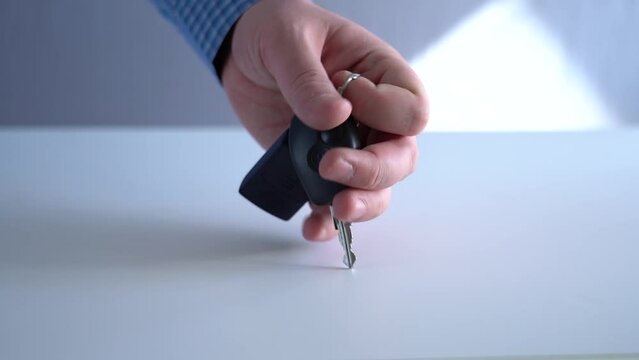 Take the key and the remote control for the car from the table.