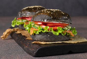 Two veggie black burger with salted salmon, crab meat and vegetables on wooden board