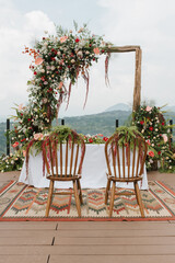 Beautiful rustic theme outdoor wedding white altar setup, with natural flower decoration and mountain background.