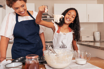 Happy girl scoops batter from a bowl with a spoon