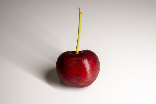 one red cherry standing in a white background